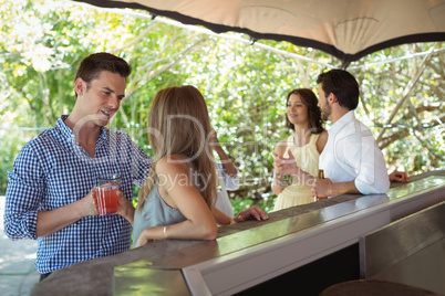 Smiling friends interacting while having a cocktail at counter