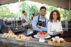 Waiter and waitress standing with clipboard at counter in restaurant