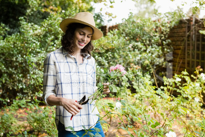 Woman trimming flowers with pruning shears in garden