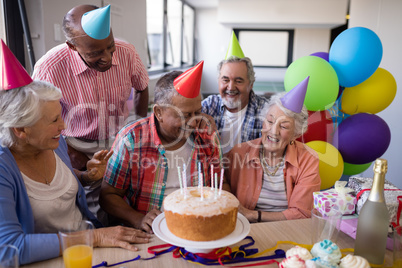 Happy senior friends by birthday cake at party