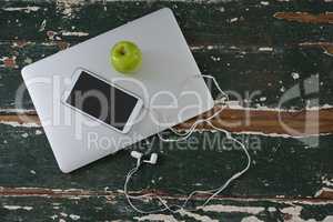 Mobile phone and green apple on laptop