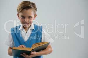 Smiling schoolboy reading book