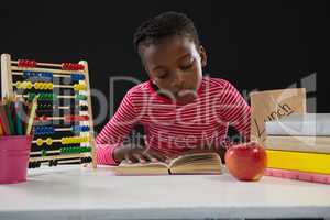 Schoolgirl reading a book against black background