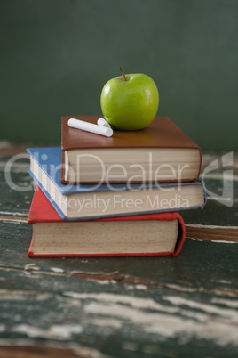 Apple and chalks on stack of books