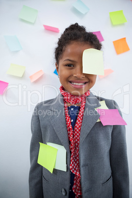 Happy businesswoman with sticky notes stuck on suit and head