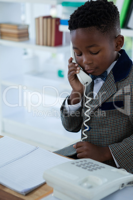 Businessman talking on landline phone while looking at book