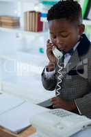 Businessman talking on landline phone while looking at book