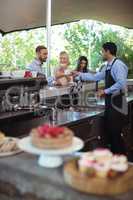 Waiter serving coffee to customer at counter