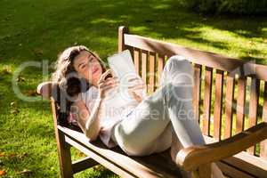 Woman lying on bench and using digital tablet in garden