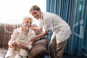 Portrait of smiling senior woman holding knit with female doctor against window