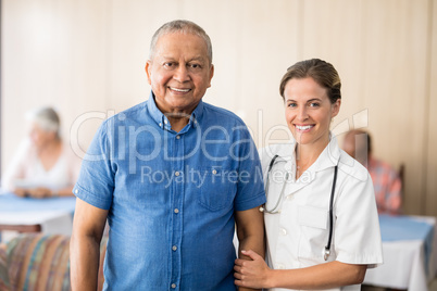 Portrait of smiling senior male patient with female doctor