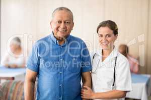 Portrait of smiling senior male patient with female doctor