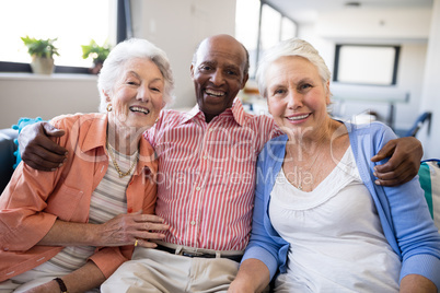 Portrait of senior man sitting with arm around over females