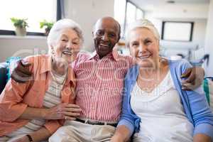 Portrait of senior man sitting with arm around over females