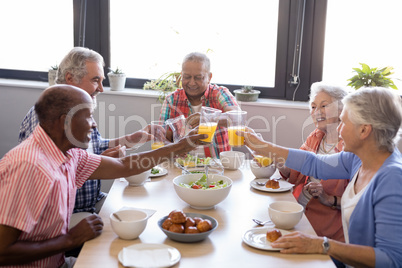Happy senior people toasting juice glasses at table