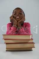 Schoolgirl relaxing in front of books stack against white background