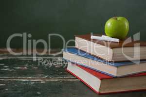 Apple and chalks on stack of books