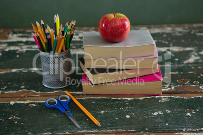 Apple on stack of books with various stationery