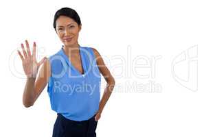 Smiling businesswoman touching interface while standing with hand on hip