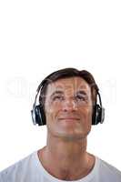 Smiling man listening music through headphones while looking up