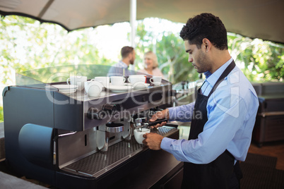 Waiter making cup of coffee from espresso machine