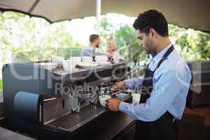 Waiter making cup of coffee from espresso machine