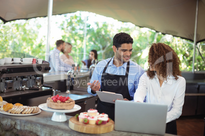 Male waiter and female waitress with laptop