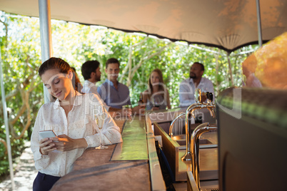 Smiling woman using mobile phone while having a glass of champagne