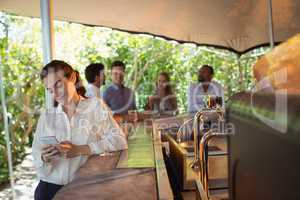 Smiling woman using mobile phone while having a glass of champagne