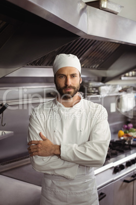 Portrait of confident chef standing with arms crossed in commercial kitchen