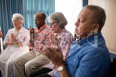 Seniors sitting on chairs while praying
