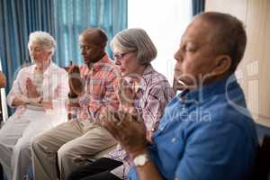 Seniors sitting on chairs while praying