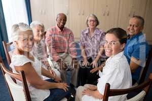 Portrait of smiling female doctor and seniors sitting on chairs