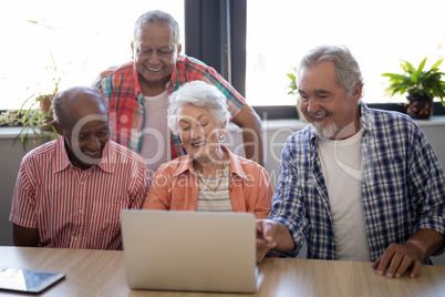 Happy senior people using laptop at table