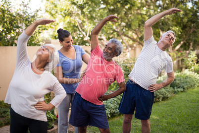 Trainer assisting senior people in exercising