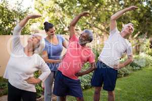 Trainer assisting senior people in exercising