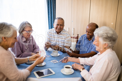 Multi-ethnic senior friends playing cards at table