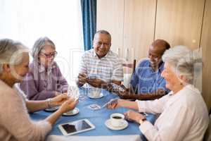 Multi-ethnic senior friends playing cards at table