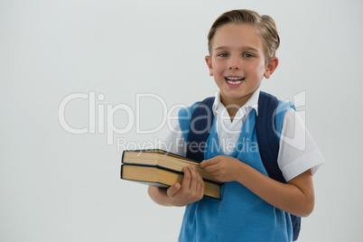 Portrait of happy schoolboy holding books against white background