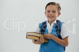 Portrait of happy schoolboy holding books against white background