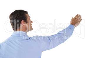 Businessman with arms raised touching invisible interface