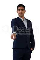 Businessman with hands in pockets touching invisible interface