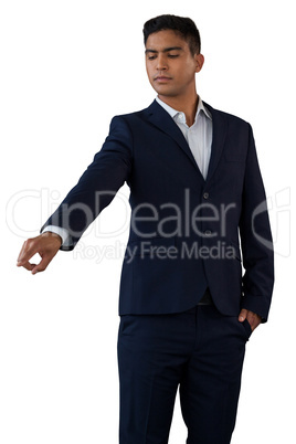Young businessman with hands in pockets touching invisible interface