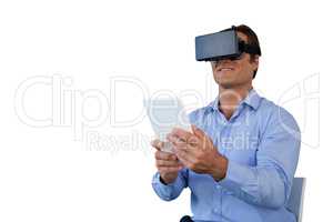 Smiling businessman with tablet sitting on chair while using vr glasses