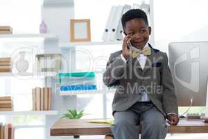 Boy imitating as businessman talking on smart phone