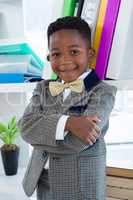 Portrait of boy imitating as businessman standing with arms crossed