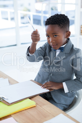 Businessman holding pen while sitting on chair
