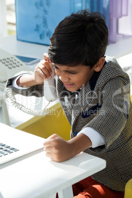 High angle view of businessman talking on teelphone while using laptop