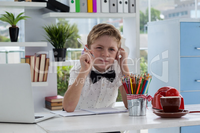 Businessman thinking while making report by laptop at desk