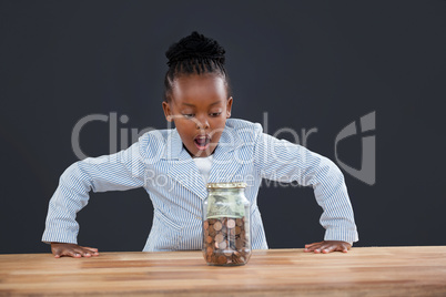 Shock businesswoman looking at coins in glass jar